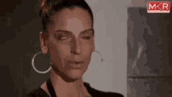 a woman wearing hoop earrings is making a funny face