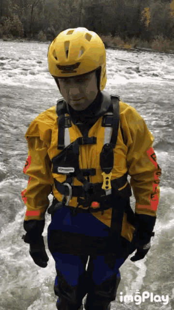 a man wearing a yellow jacket and a yellow helmet is walking across a river ..