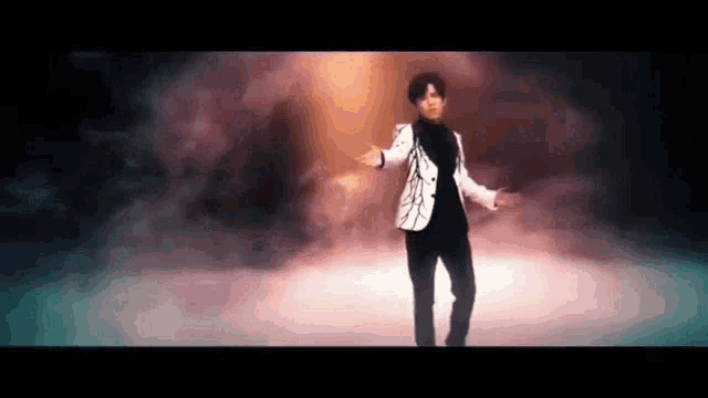 a man in a white jacket is dancing on a stage .