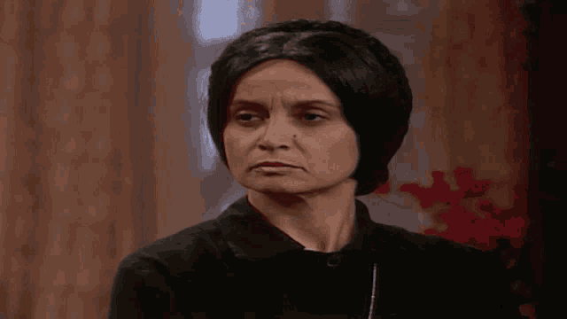 a woman in a black shirt is making a funny face in a room .