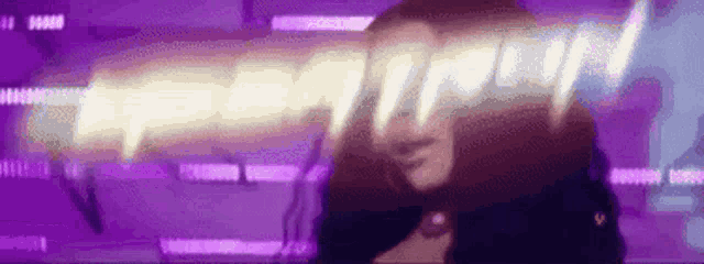a woman is standing in front of a purple background with a purple light coming out of her face .