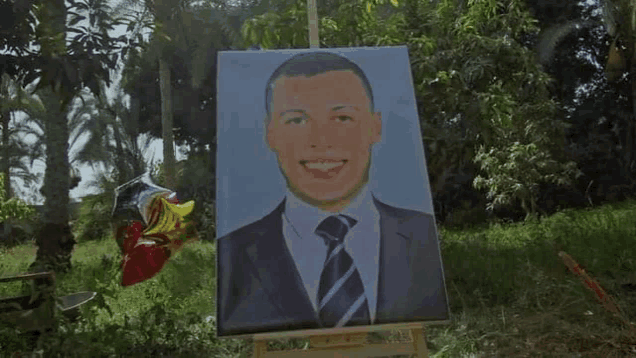 a painting of a man in a suit and tie is on a wooden easel in the grass .