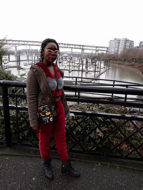 a woman standing on a bridge overlooking a body of water with boats docked