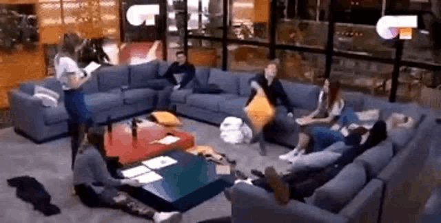 a group of people are sitting on couches in a living room with a woman standing in the middle .