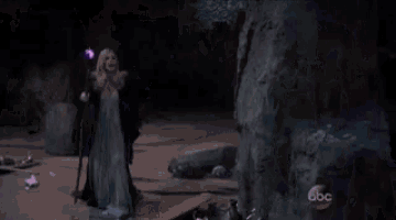 a person is standing in a cave with a purple light in the background .