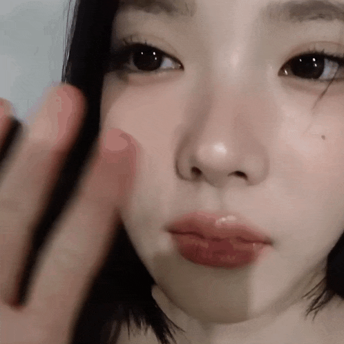 a close up of a woman 's face with her finger on her face .