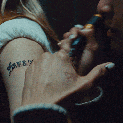 a woman has a tattoo on her arm that says love & e