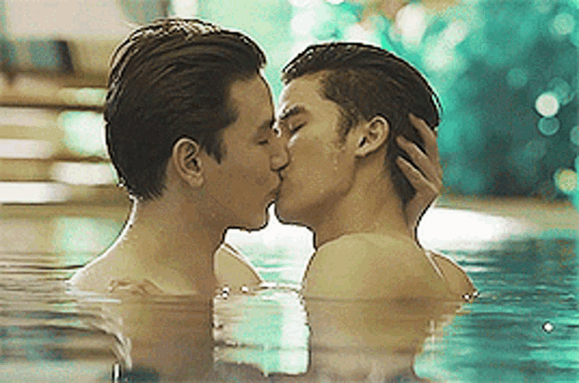 two men kissing in a pool of water