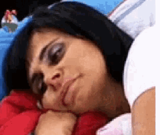 a woman is laying in bed with her head on her hand and her eyes closed .