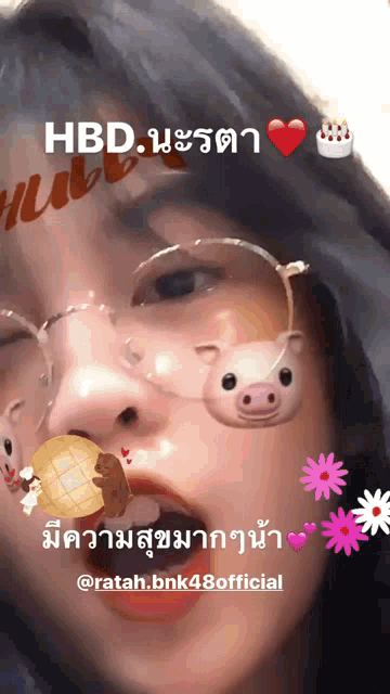 a girl wearing glasses has a pig necklace around her neck and a birthday cake in the background