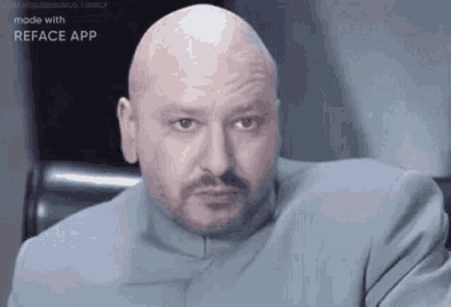 a bald man with a beard is sitting in a chair and making a face .