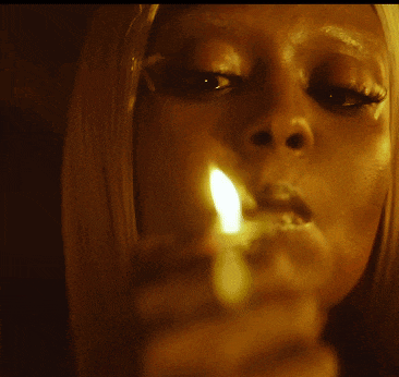 a woman with long nails is smoking a cigarette in the dark