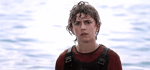 a young man is standing in front of a body of water wearing a life vest .