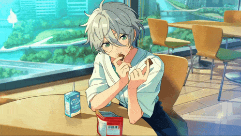 a boy with gray hair is sitting at a table with a carton of milk