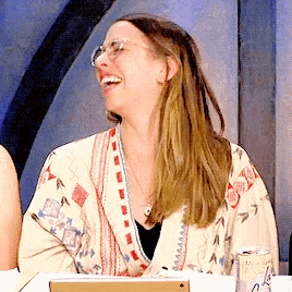 a woman wearing glasses is laughing while sitting at a desk