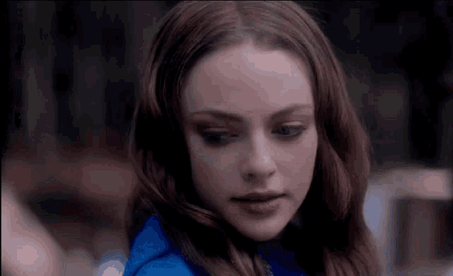 a close up of a woman 's face with long hair wearing a blue jacket .