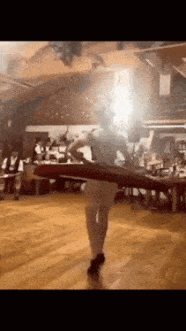a woman is dancing on a wooden floor in front of a crowd of people