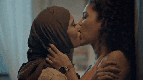 a woman in a hijab kissing another woman