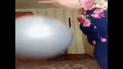 a person in a floral dress is playing with a large white ball .
