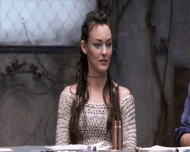 a woman wearing a choker sits at a table with dice