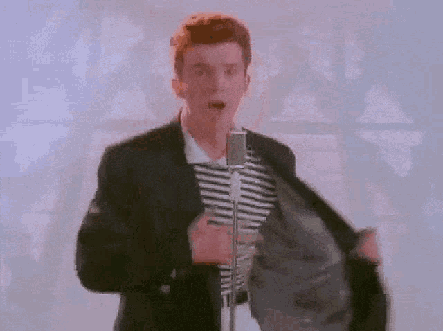 a man is singing into a microphone with his jacket open