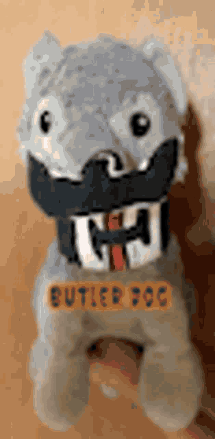 a person is holding a stuffed animal that looks like a dog with a collar on it .