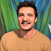 a man with a beard and mustache is smiling in front of a colorful background .