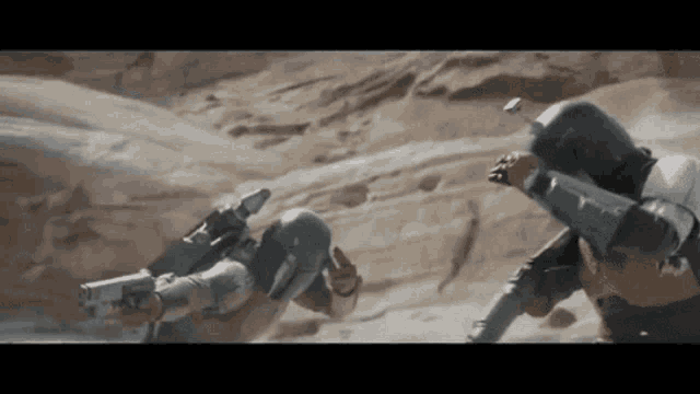 two soldiers are fighting in the desert and one of them has a gun