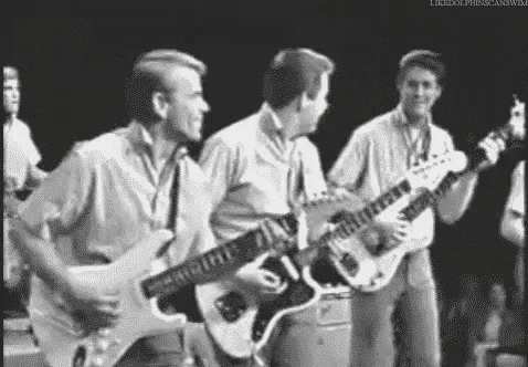 three men are playing guitars on stage in a black and white photo .