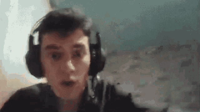 a man wearing headphones is looking at the camera and making a surprised face .