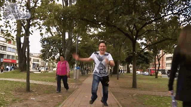 a man is jumping in the air in a park with a bank of america building in the background
