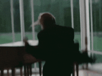 a blurry picture of a person sitting in front of a piano in a room .