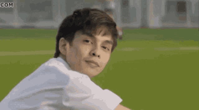 a young boy is sitting on the grass and smiling .