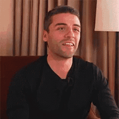 a man in a black shirt is smiling while sitting in a chair .