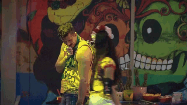 a man and a woman are dancing in front of a day of the dead wall