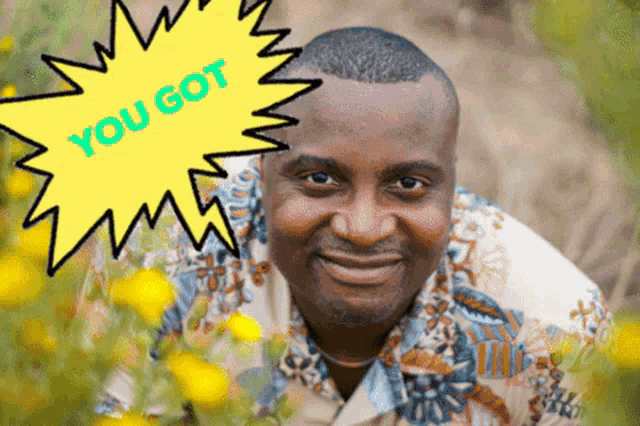 a man is smiling in front of a yellow sign that says " you got "