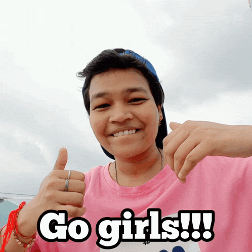 a woman in a pink shirt giving a thumbs up and says go girls
