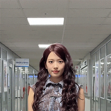 a woman stands in a hallway with a kbs sign on the wall