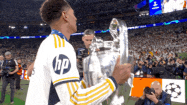 a soccer player wearing an hp shirt is holding a trophy