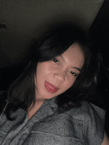 a woman in a gray shirt is sticking her tongue out