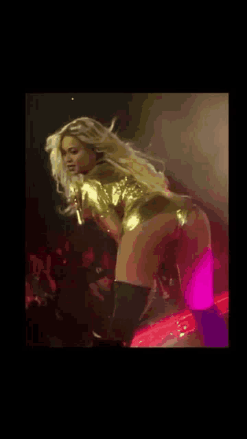 a woman in a gold dress is dancing on a stage .