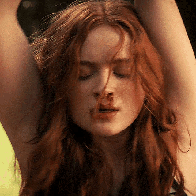 a close up of a woman 's face with her eyes closed and her hair blowing in the wind