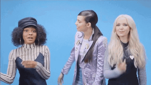 three women are standing next to each other on a blue background .