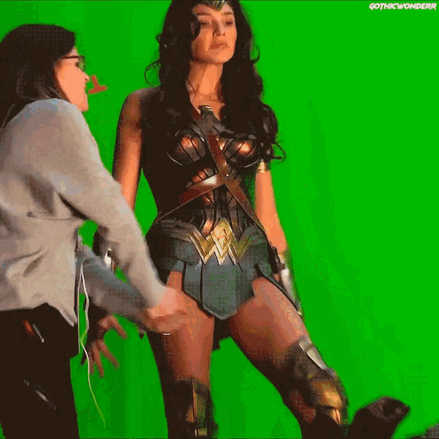 a woman in a wonder woman costume stands in front of a green background