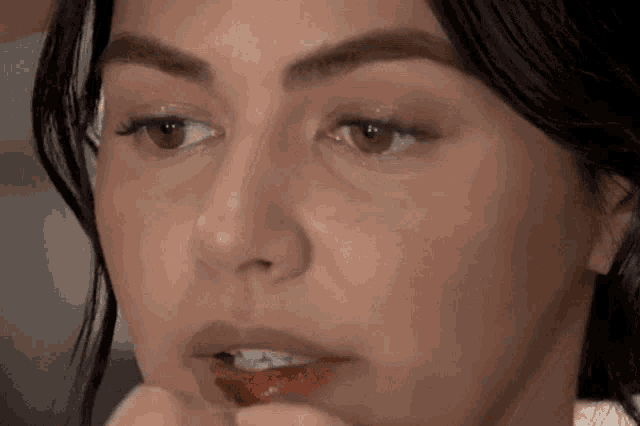 a close up of a woman applying lip gloss on her lips .