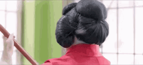 a woman in a red dress is holding a wooden stick in her hair .