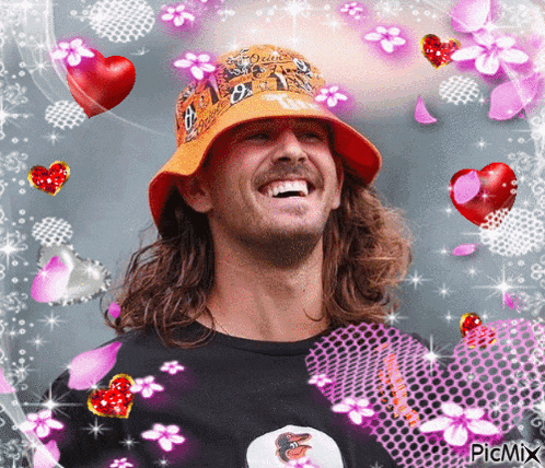 a man wearing an orange hat with the letter t on it is surrounded by pink flowers and hearts