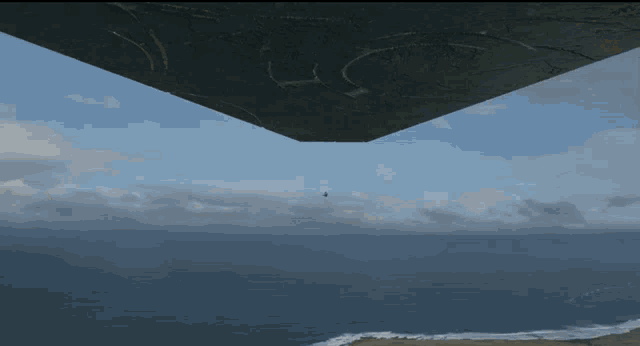 a plane is flying over a body of water and a light is coming out of it
