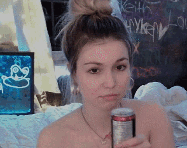 a woman is holding a can of soda in front of a chalkboard with the name keith written on it