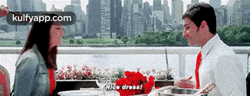a man and a woman are sitting at a table and the man is saying " nice dress "